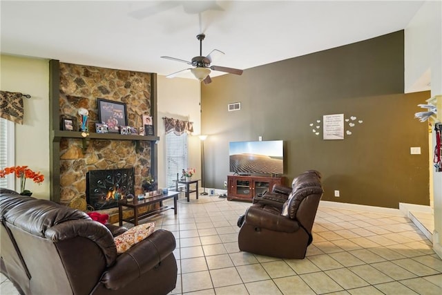 living room with a healthy amount of sunlight, light tile patterned floors, visible vents, and a stone fireplace