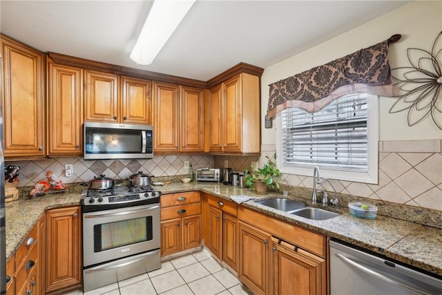 kitchen with appliances with stainless steel finishes, brown cabinetry, and a sink