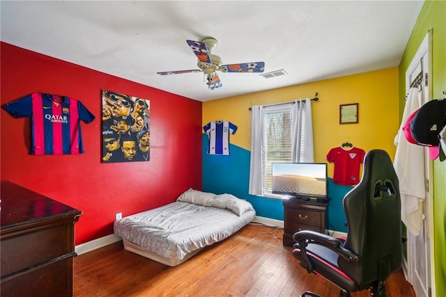 bedroom with baseboards, visible vents, ceiling fan, and wood finished floors