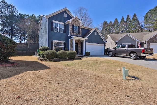 traditional-style home featuring a front yard, stone siding, a garage, and driveway