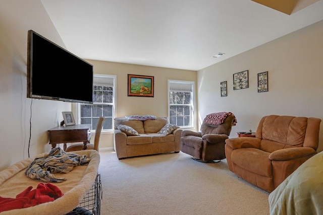 living area featuring a wealth of natural light, visible vents, and carpet