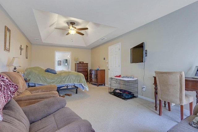 carpeted bedroom with visible vents, baseboards, a raised ceiling, and a ceiling fan