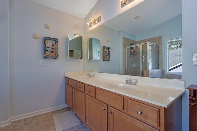 full bath with a stall shower, a sink, double vanity, baseboards, and vaulted ceiling