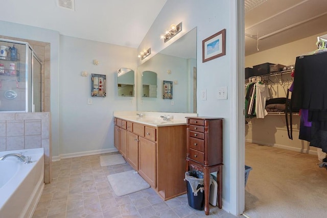 bathroom featuring visible vents, a sink, a shower stall, a spacious closet, and a garden tub