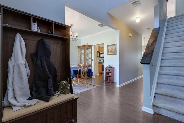 mudroom featuring baseboards, visible vents, dark wood finished floors, ornamental molding, and a notable chandelier