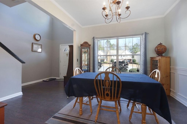 dining area featuring a wainscoted wall, ornamental molding, wood finished floors, an inviting chandelier, and baseboards