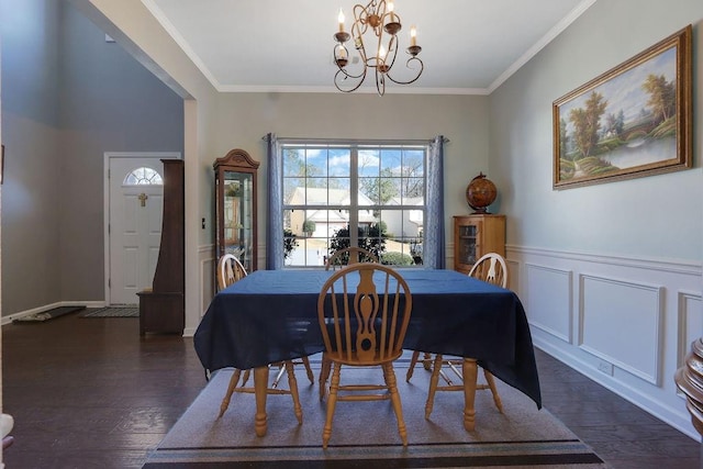 dining room featuring dark wood-style floors, a notable chandelier, crown molding, and a wainscoted wall