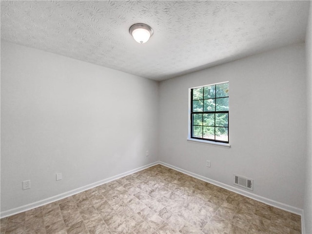 tiled empty room with a textured ceiling