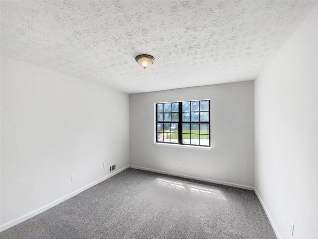 unfurnished room with a textured ceiling and carpet floors