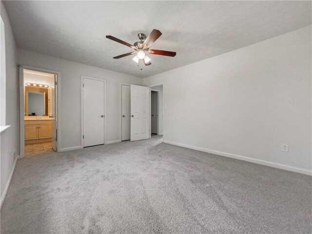 unfurnished bedroom featuring ceiling fan, light carpet, and ensuite bathroom