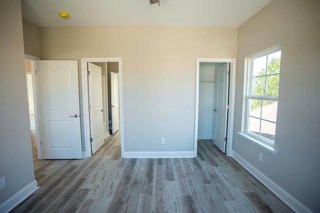 unfurnished bedroom featuring hardwood / wood-style floors, a walk in closet, and a closet