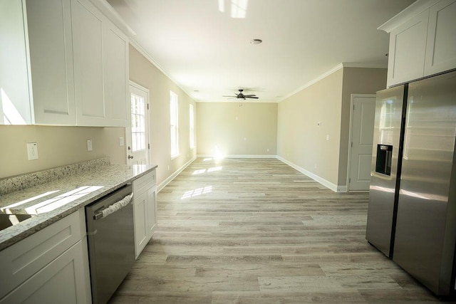 kitchen with white cabinetry, ornamental molding, ceiling fan, stainless steel appliances, and light stone countertops