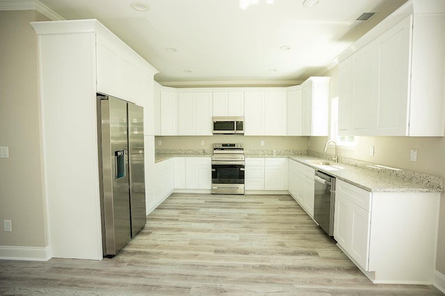 kitchen with white cabinetry, sink, light stone countertops, and appliances with stainless steel finishes