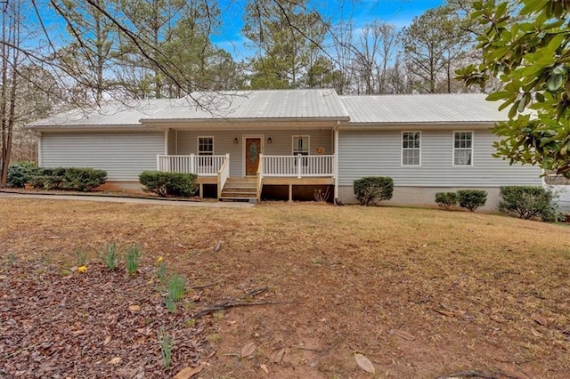 ranch-style home featuring metal roof, covered porch, and a front yard