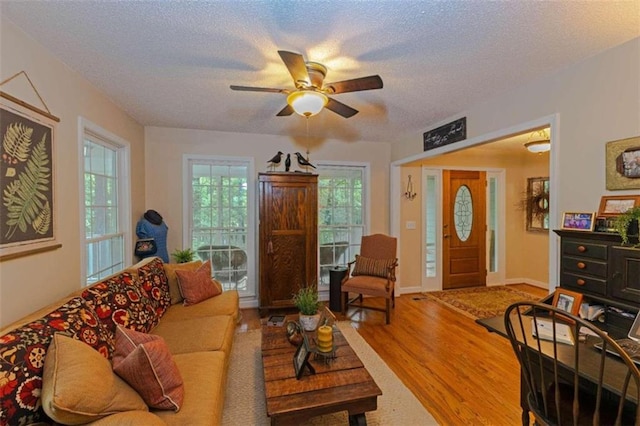 living room with a textured ceiling, hardwood / wood-style floors, and ceiling fan