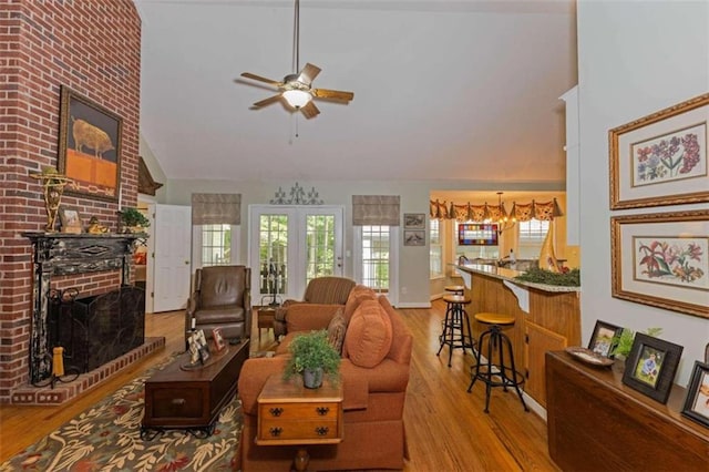 living room featuring light hardwood / wood-style floors, a fireplace, brick wall, and ceiling fan