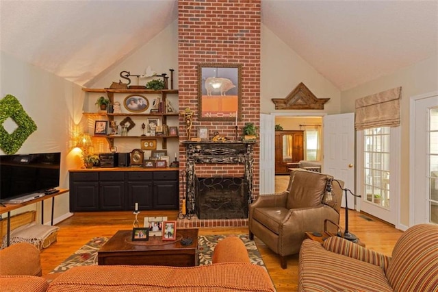 living room with a fireplace, brick wall, light wood-type flooring, and high vaulted ceiling