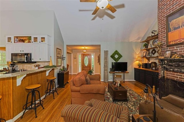 living room featuring high vaulted ceiling, brick wall, ceiling fan, and hardwood / wood-style floors