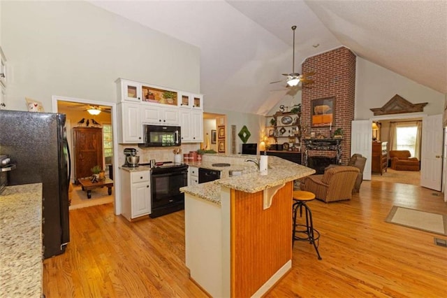 kitchen featuring black appliances, brick wall, a kitchen bar, and ceiling fan