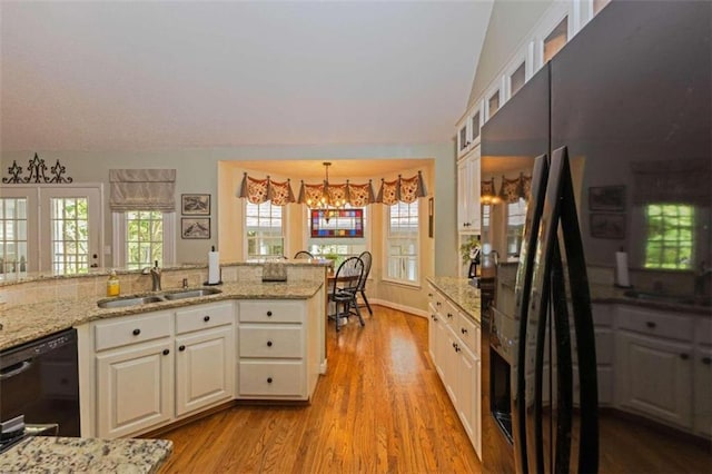 kitchen featuring white cabinetry, black appliances, pendant lighting, sink, and light hardwood / wood-style flooring