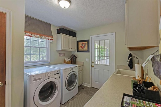 washroom with washing machine and clothes dryer, sink, a textured ceiling, and cabinets