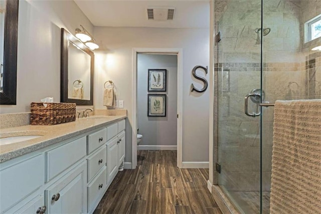 bathroom featuring dual vanity, an enclosed shower, hardwood / wood-style floors, and toilet