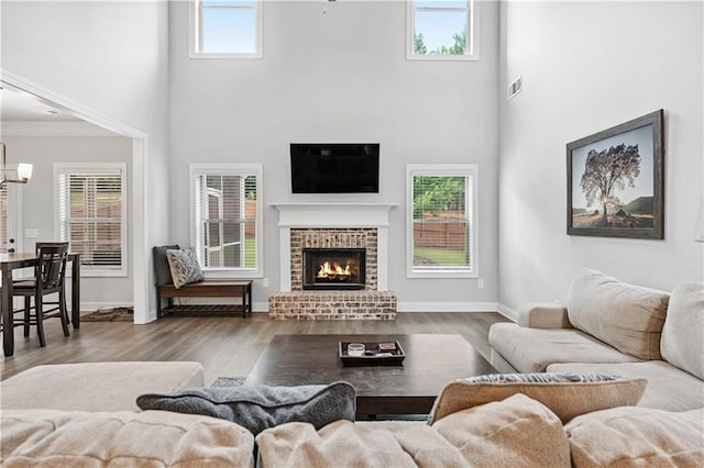 348 Meeler Cir, Bogart, GA 30622 - living area with a towering ceiling, wood finished floors, a brick fireplace, a chandelier, and crown molding