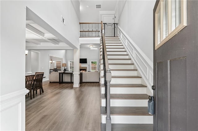 348 Meeler Cir, Bogart, GA 30622 - staircase featuring a warm lit fireplace, wood finished floors, beamed ceiling, a high ceiling, and coffered ceiling