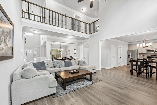 348 Meeler Cir, Bogart, GA 30622 - living area featuring a chandelier, a towering ceiling, a ceiling fan, light wood-style floors, and ornamental molding