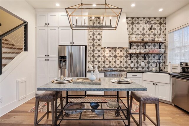 kitchen with white cabinets, light wood-type flooring, sink, appliances with stainless steel finishes, and backsplash