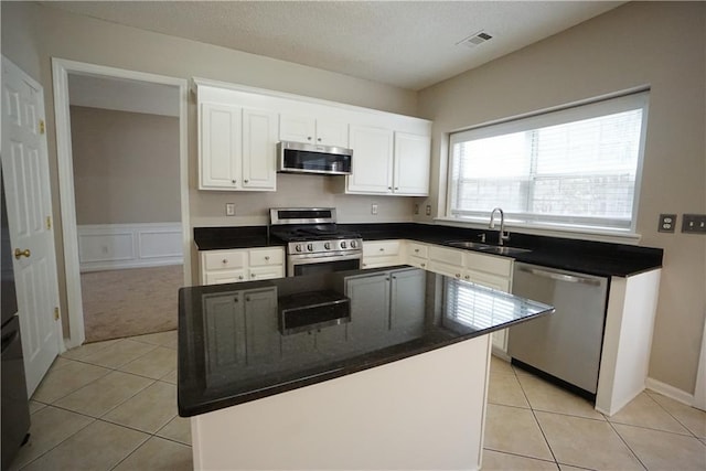 kitchen featuring white cabinetry, sink, a center island, stainless steel appliances, and light tile patterned flooring