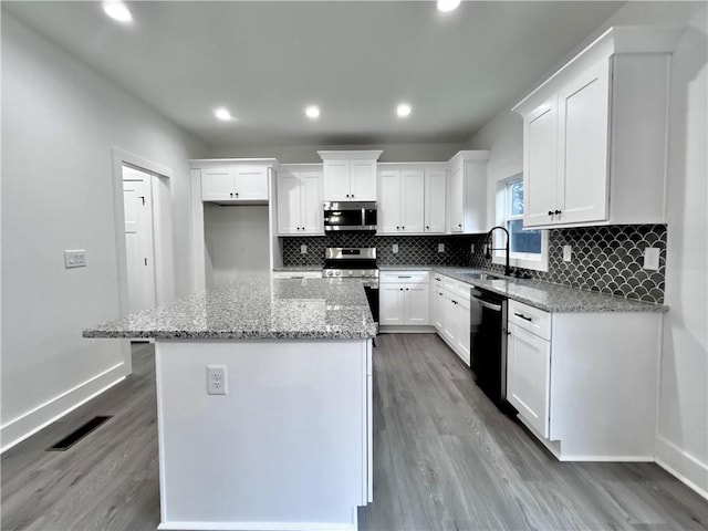 kitchen featuring sink, white cabinetry, a kitchen island, stainless steel appliances, and light stone countertops