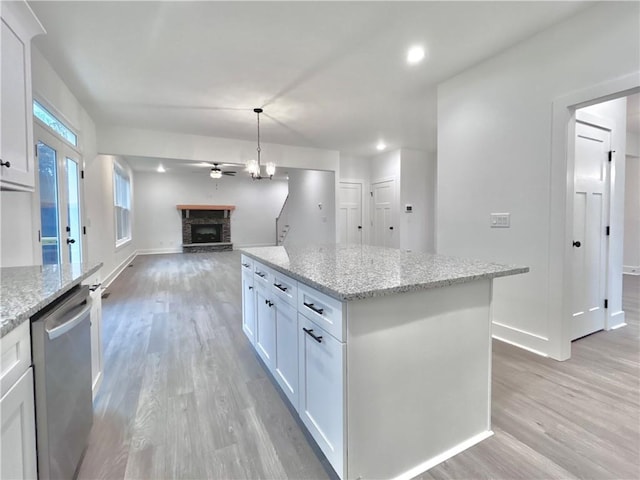 kitchen with white cabinetry, a kitchen island, stainless steel dishwasher, and decorative light fixtures