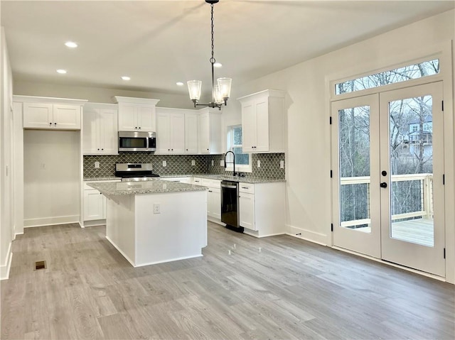 kitchen with stainless steel appliances, white cabinetry, a kitchen island, and french doors