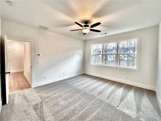 carpeted spare room featuring a textured ceiling and ceiling fan