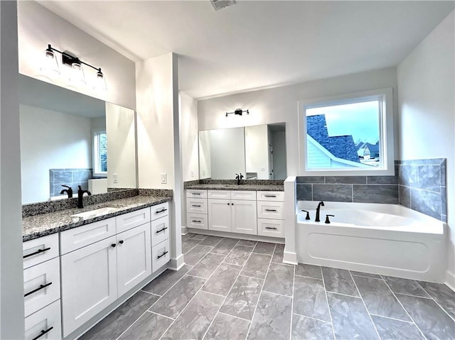 bathroom with vanity, a wealth of natural light, and a bathing tub