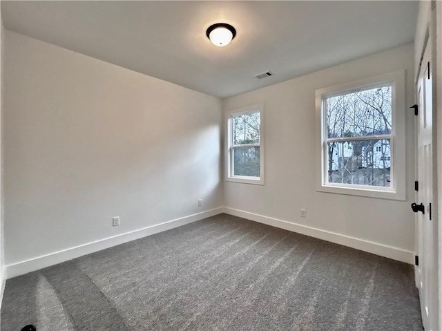 spare room featuring dark carpet