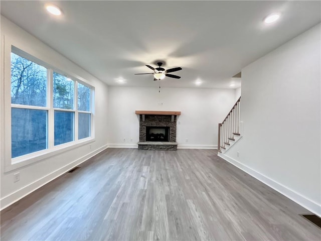 unfurnished living room featuring hardwood / wood-style floors, a fireplace, and ceiling fan