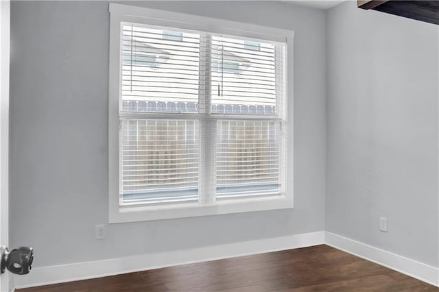 spare room featuring dark wood-style flooring and baseboards