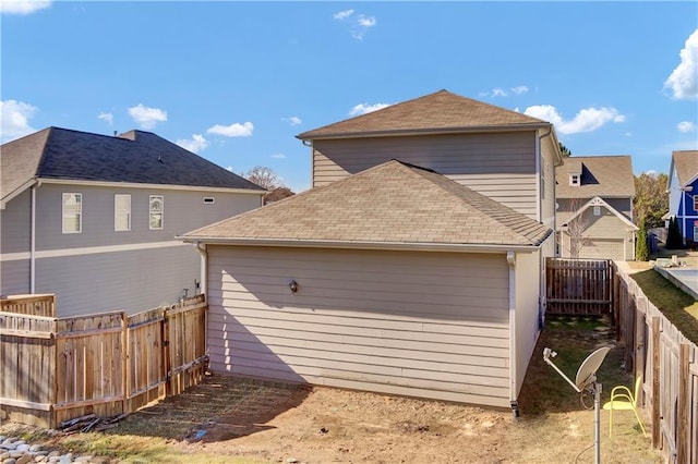 back of house with a fenced backyard and a shingled roof