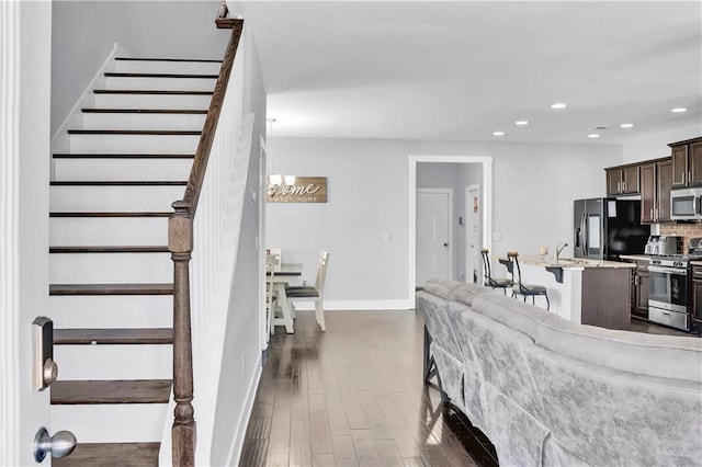 living area featuring baseboards, stairway, dark wood finished floors, and recessed lighting