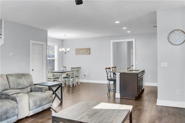 living area with recessed lighting, a notable chandelier, dark wood finished floors, and baseboards