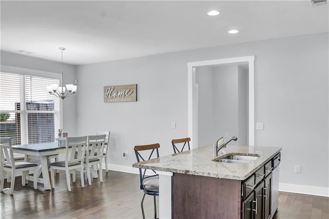 kitchen with dark wood-type flooring, baseboards, a kitchen breakfast bar, and a sink