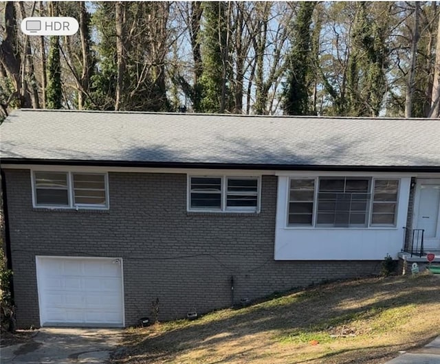 view of side of home with driveway, brick siding, and an attached garage