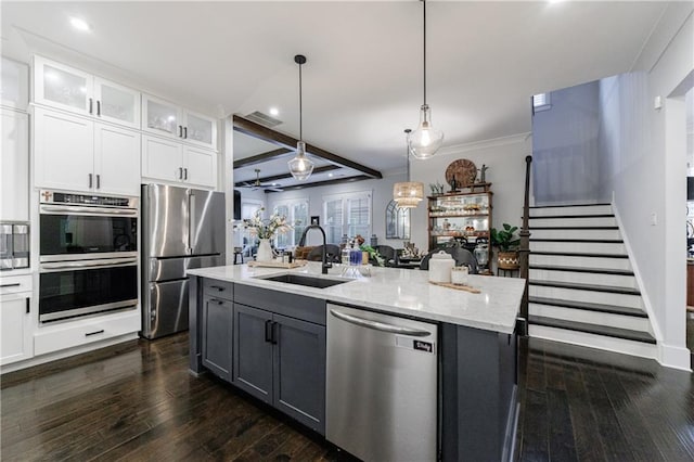 kitchen with pendant lighting, white cabinets, a center island with sink, sink, and appliances with stainless steel finishes