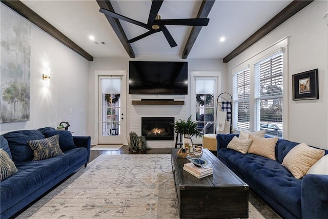 living room with beamed ceiling, ceiling fan, and a fireplace