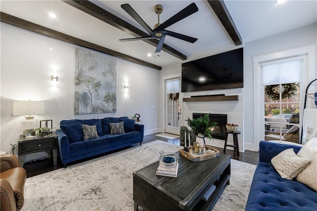 living room featuring beam ceiling, a fireplace, ceiling fan, and hardwood / wood-style floors