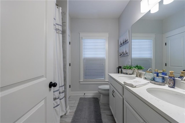 bathroom with vanity, toilet, and a healthy amount of sunlight