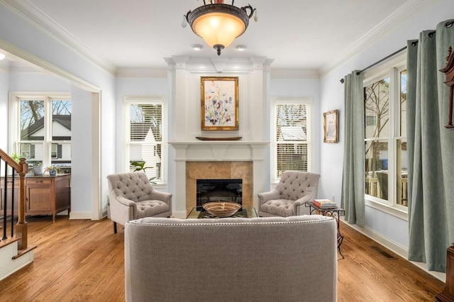 living area featuring a tile fireplace, crown molding, and light hardwood / wood-style flooring