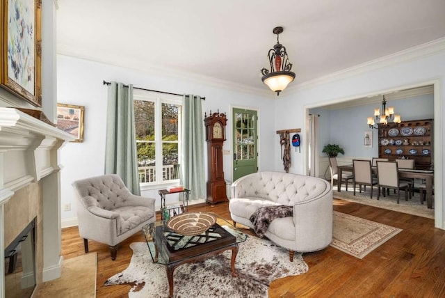 living room featuring ornamental molding, a chandelier, a fireplace, and wood-type flooring